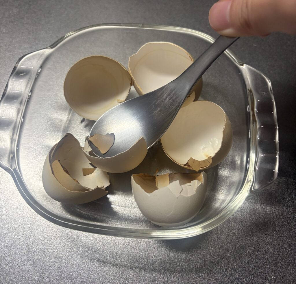 スプーンで大まかに卵の殻を砕く